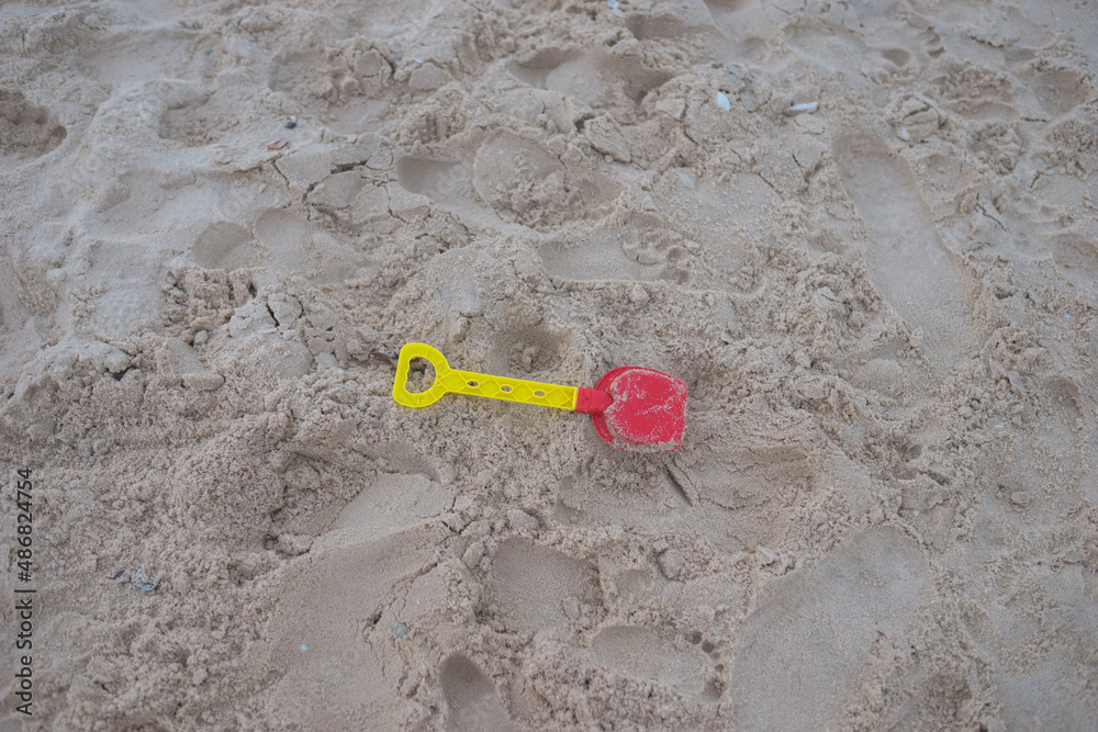 Childrens toy shovel for playing in the sand lies on the beach. Kids toy on the beach. High quality photo Childrens toy shovel for playing in the sand lies on the beach. Kids toy on the beach. High quality photo