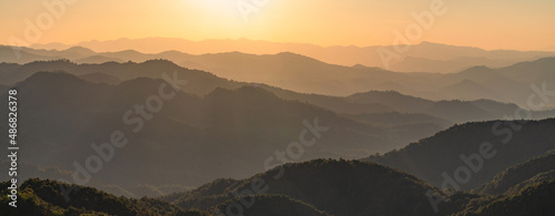 Beautiful dark orange mountain landscape with fog and forest. sunrise and sunset in mountains, Layers of mountain orange rocky hills landscape background.