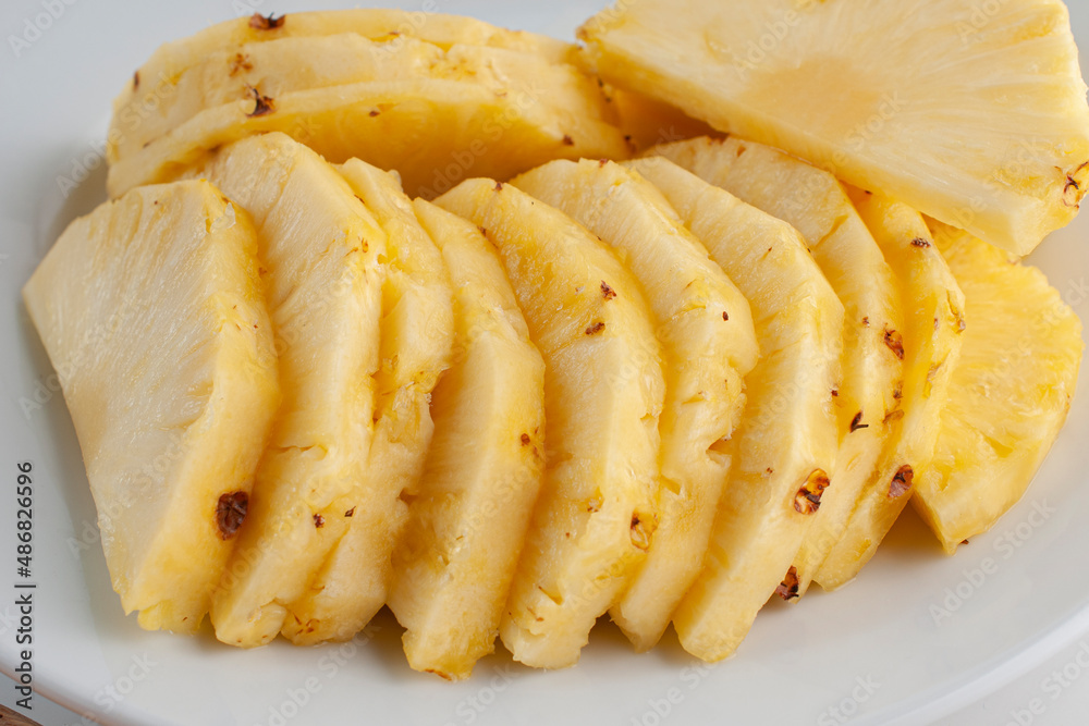 Pineapple slices on a white plate as part of healthy foods concepts. Macro photohgraphy, side view. Pineapple slices on a white plate as part of healthy foods concepts. Macro photohgraphy, side view.