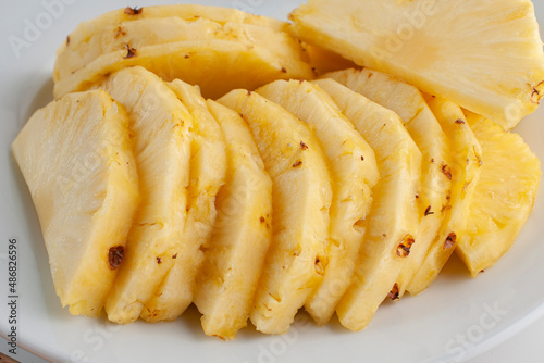 Pineapple slices on a white plate as part of healthy foods concepts. Macro photohgraphy, side view.