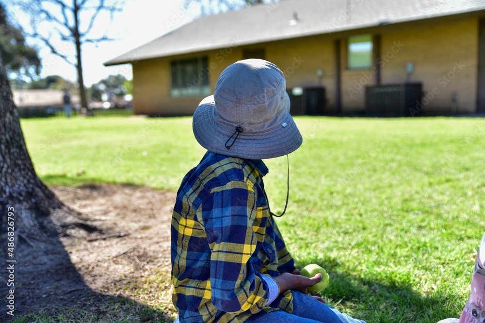 Side profile of a boy wearing a large floppy hat