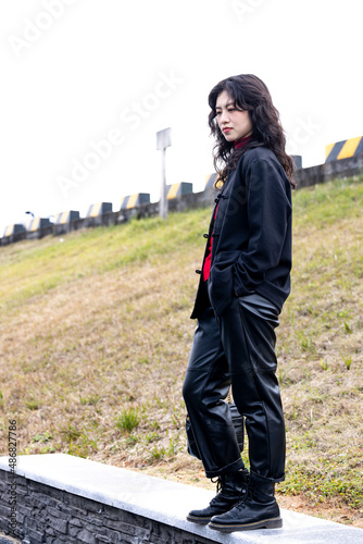 An Asian woman in a black leather coat outdoors