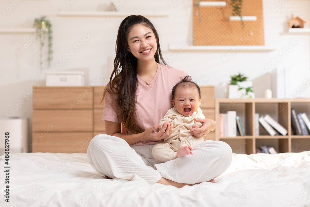 Adorable newborn baby smile and relax in mother arm safety and comfortable.Healthy Asian newborn infant baby laughing with happiness good moment.Mother holding infant baby.Newborn Baby concept Adorable newborn baby smile and relax in mother arm safety and comfortable.Healthy Asian newborn infant baby laughing with happiness good moment.Mother holding infant baby.Newborn Baby concept