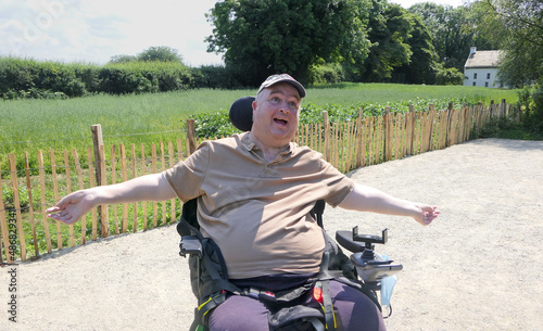 Wheelchair user sitting in the sun with his arms spread photo