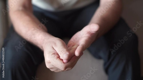 An elderly man rubs and massages sore finger joints with symptoms of pain in arthritis, arthrosis, periarthritis. Usage for healthcare and medicine product concept photo