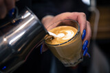 Close up hand of a woman barista pouring froth milk in espresso coffee.