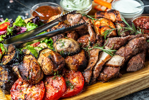 delicious grilled meat with vegetable. Mixed grilled bbq meat with vegetables on wooden platter. Restaurant menu, dieting, cookbook recipe top view
