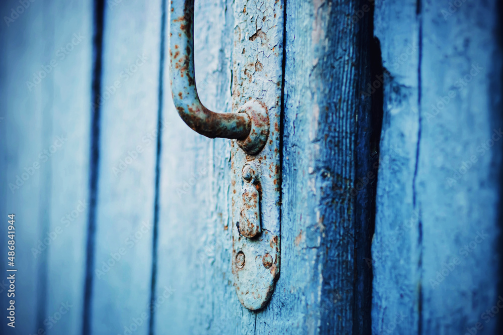 An old blue wooden door with a rusty metal handle. A closed door to the house. The mystery is behind the door. Retro.
