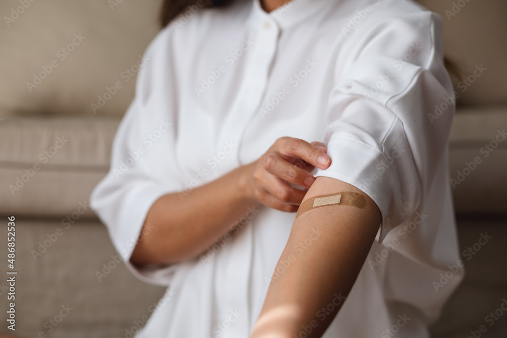 Closeup image of a woman with adhesive bandage, medical plaster, band aid on her arm