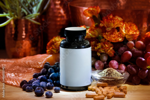 Blank label medicine pill bottle surrounded by fresh food ingredients like salmon, berries, and nuts photo
