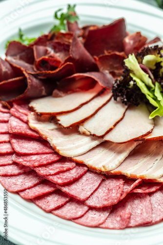 Cured meat platter of sliced ham, sausage, prosciutto, bacon. Meat antipasto, banner, menu, recipe place for text, top view
