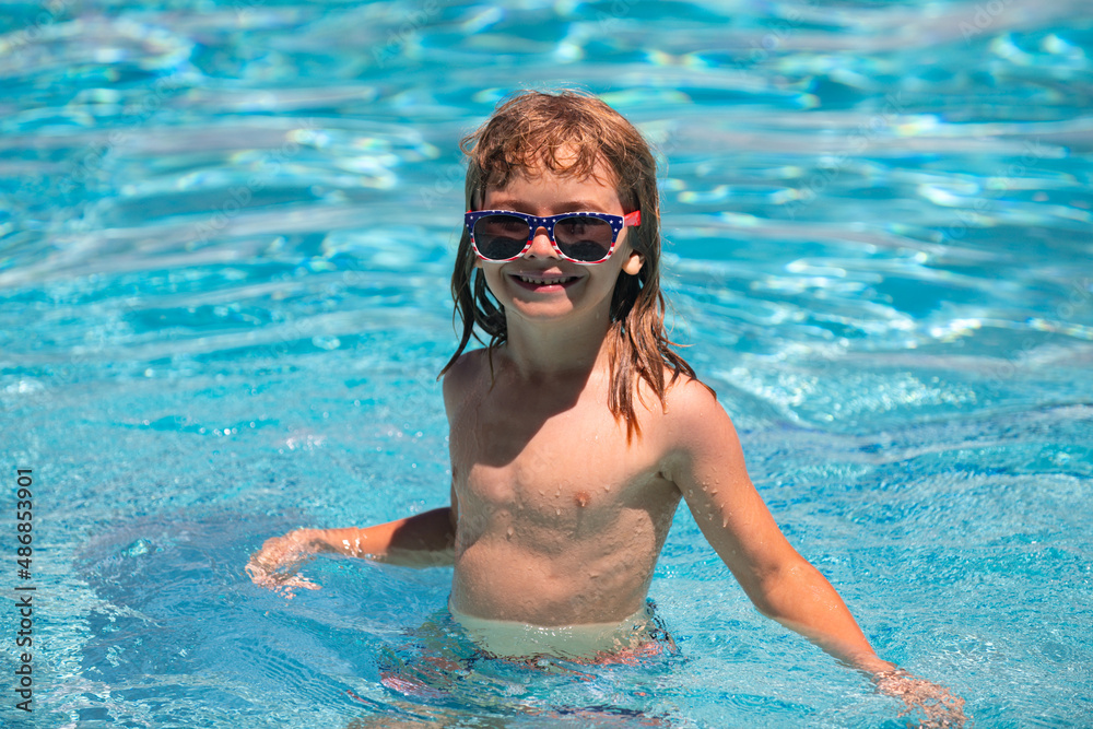 Fototapeta premium Cute child boy swim in swimming pool, summer water background with copy space. Funny kids face. Summertime and swimming activities for children on the pool.