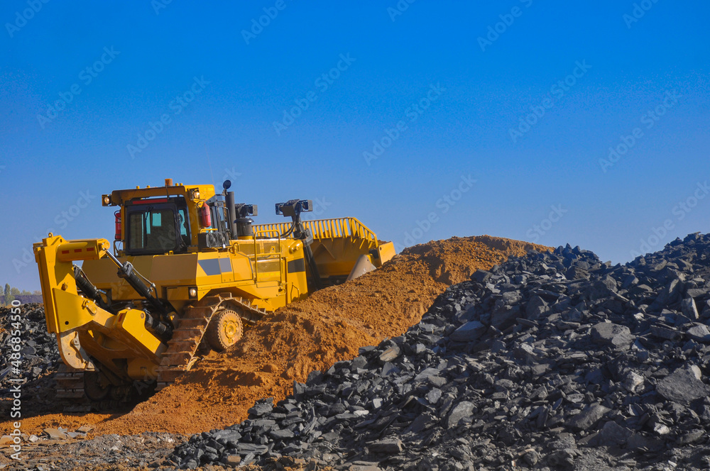Bulldozer working in an iron ore quarry. Bulldozer clears the road from the rock mass. Buddozer builds a road in a quarry. Bulldozer working in an iron ore quarry. Bulldozer clears the road from the rock mass. Buddozer builds a road in a quarry.