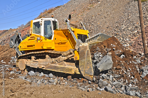 Bulldozer working in an iron ore quarry. Bulldozer clears the road from the rock mass. Buddozer builds a road in a quarry.
