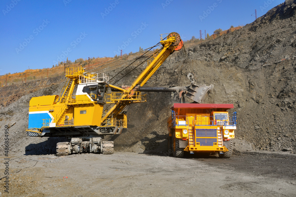 Excavator in the quarry loads the dumper with iron ore. Excavator in the quarry loads the dumper with iron ore.
