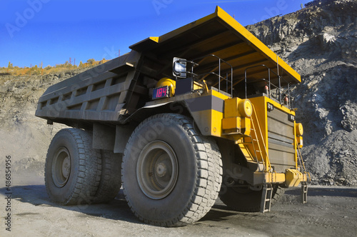  Mining dump truck transports rock, iron ore along the side of the quarry.