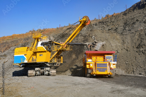 Excavator in the quarry loads the dumper with iron ore.