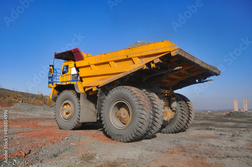 Obraz na plátně Mining dump truck transports rock, iron ore along the side of the quarry