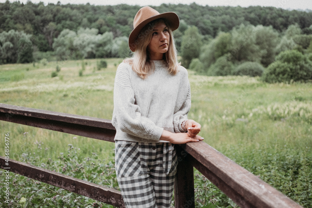Young cheerful woman in hat on nature. Neutral colours on nature