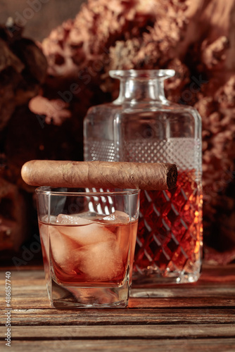 Whiskey with ice and cigar on an old wooden table.