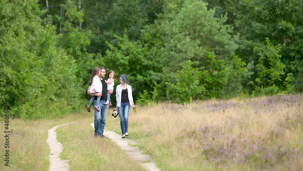 Happy young family walking along a country road in the park. Happy Family Walking Outdoors. Happy young family walking along a country road in the park. Happy Family Walking Outdoors.