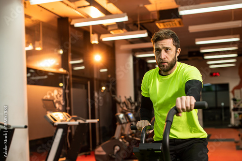 Dedicated sportsman exercising in gym. Fit male athlete is doing cardiovascular exercise. He is wearing sportswear.