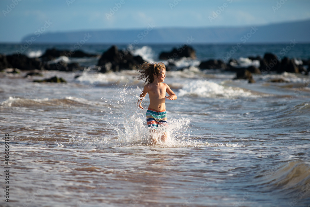 Fototapeta premium Child boy on the coast. Little kid playing in the ocean. Holidays on the sea. The child in waves.