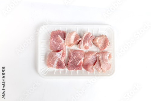 Raw pork belly on a white plastic tray on a white background