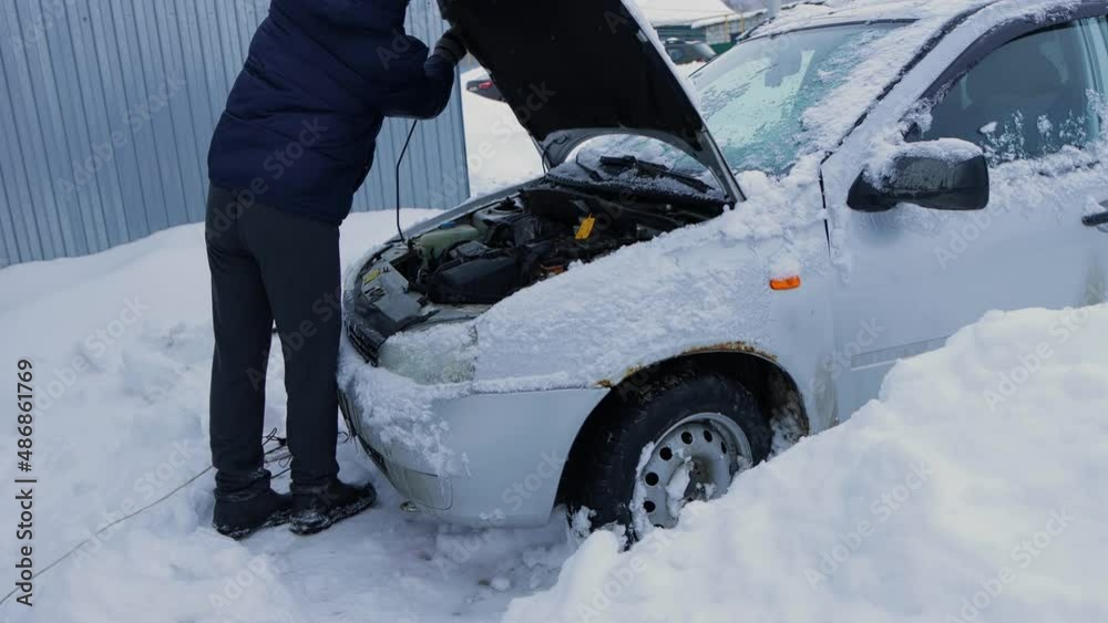 a man charges a dead battery on an old car in winter a man charges a dead battery on an old car in winter