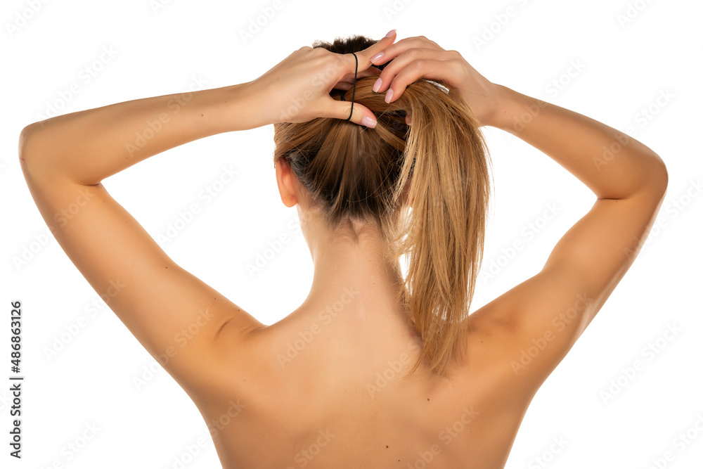 Fototapeta premium Rear view of a young woman tying her long hair
