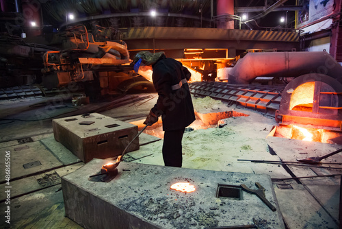 Temirtau, Kazakhstan - June 08, 2012: Arcelor Mittal metallurgy plant. Steel manufacturing in Smelter. Metallurgist take samples of steel. Electric arc furnace on background. photo