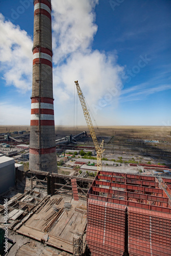 Aerial view of GRES-1 steam power station.Construction of new raw coal bunkers.Yellow crane, smoke stack.Coal harvesters and conveyor on background.Blue sky.Ekibastuz, Pavlodar reg., Kazakhstan. photo