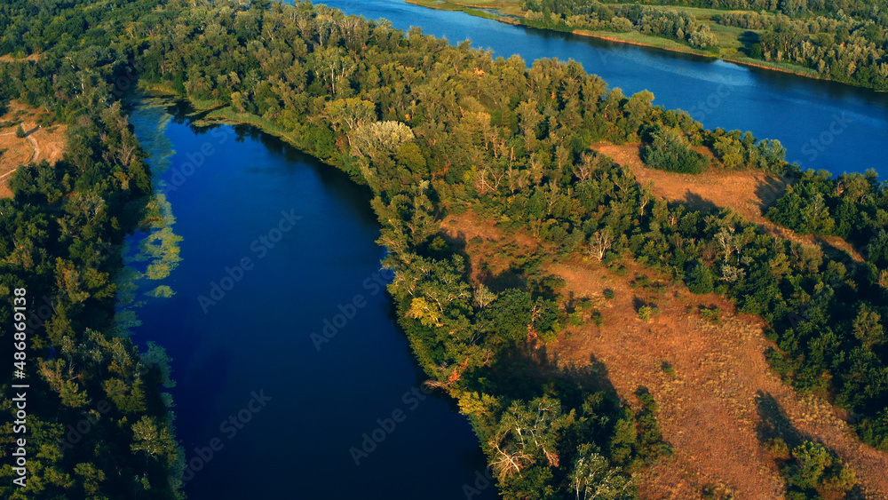 Beautiful summer landscape while sunset over the river with a drone. Aerial view on a green wild nature landscape. Beautiful  lake with small islands - drone shooting.
