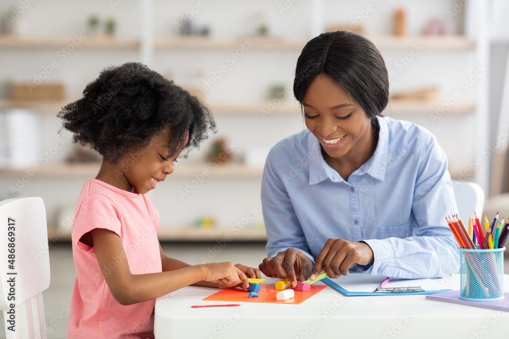 Adorable little black girl and teacher playing with play dough Adorable little black girl and teacher playing with play dough
