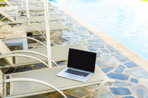 laptop on a sun lounger near the swimming pool.