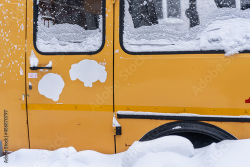 The yellow bus is covered with snow