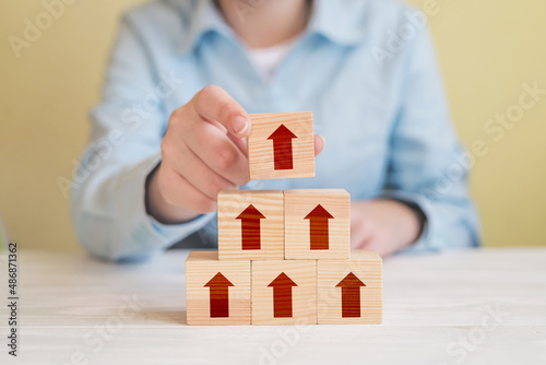 Φωτογραφία Hand picked wood cube block with arrow on top pyramid