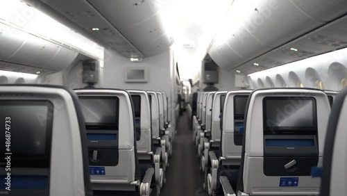 Moving down an aisle of a 787 commercial passenger airplane, viewing the seatbacks with inflight entertainment.