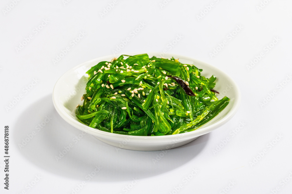 Chuka Seaweed Salad with sesame seeds isolated on white background. Trendy hard light, dark shadow