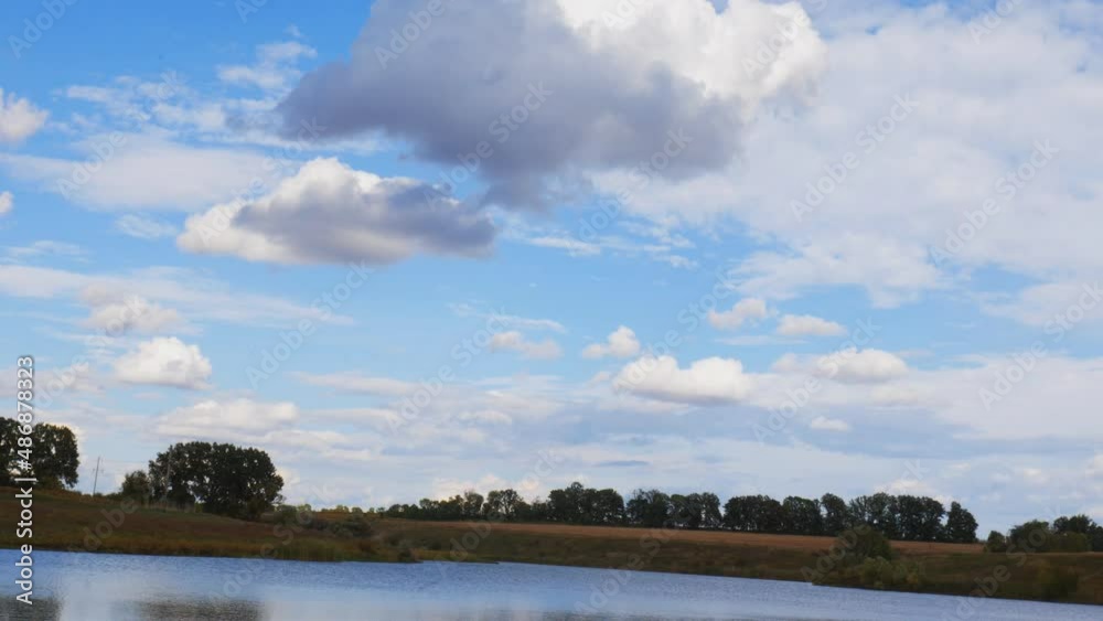 A picturesque skyline in summer with beautiful clouds reflecting in the water and trees on the horizon A picturesque skyline in summer with beautiful clouds reflecting in the water and trees on the horizon