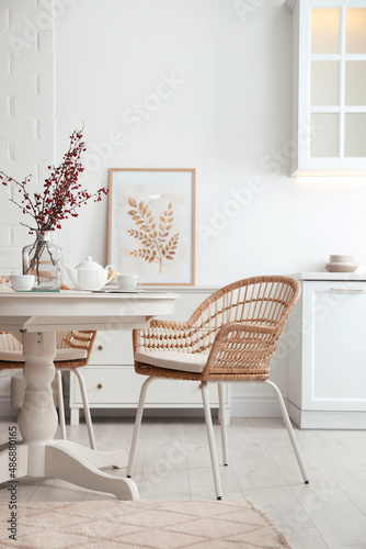 Dining room interior with tea set on round table and wicker chairs