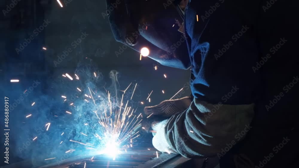 Close-up of metal welding, blue glow, red sparks flies, welding arc, metal melts, metal construction