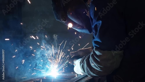 Close-up of metal welding, blue glow, red sparks flies, welding arc, metal melts, metal construction photo