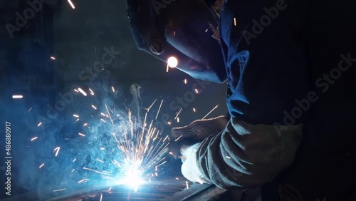 Close-up of metal welding, blue glow, red sparks flies, welding arc, metal melts, metal construction