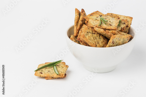 Square crackers with herbs, leenseed and spices in white form on white background. Herbal crunchy diet cookies with green rosemary photo