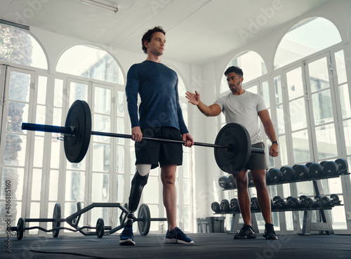 Fotografie differently abled athlete weightlifting with his coach in the gym