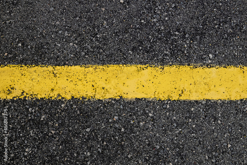 Yellow stripe on black asphalt background.