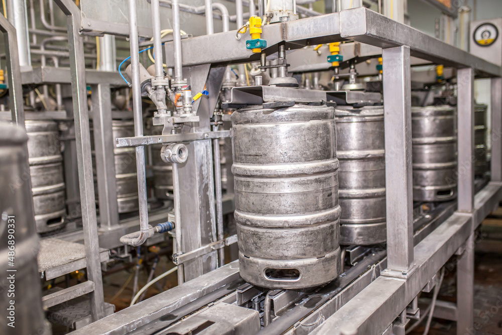Brewery, bottling beer on aluminum kegs on conveyor lines. Industrial work, automated modern food and beverage production. Brewery, bottling beer on aluminum kegs on conveyor lines. Industrial work, automated modern food and beverage production.