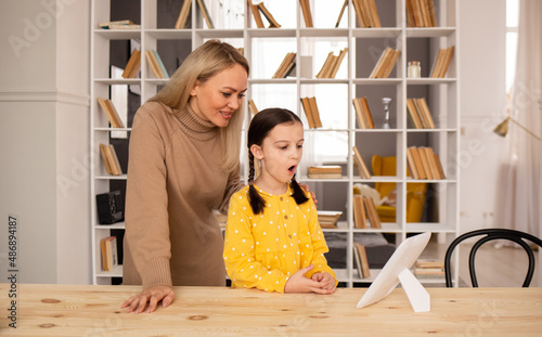 a speech therapist woman teaches correct pronunciation with the help of a mirror to a little girl student. Diction problems