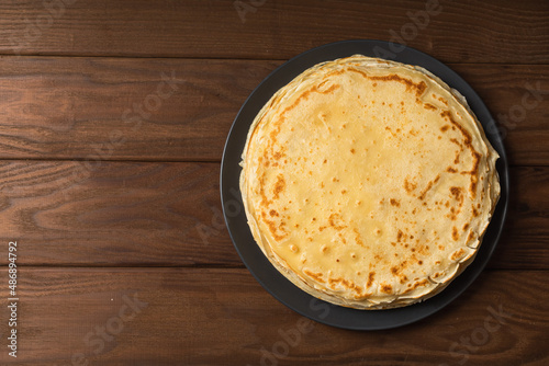 Pancake on the black plate on wooden table. Top view